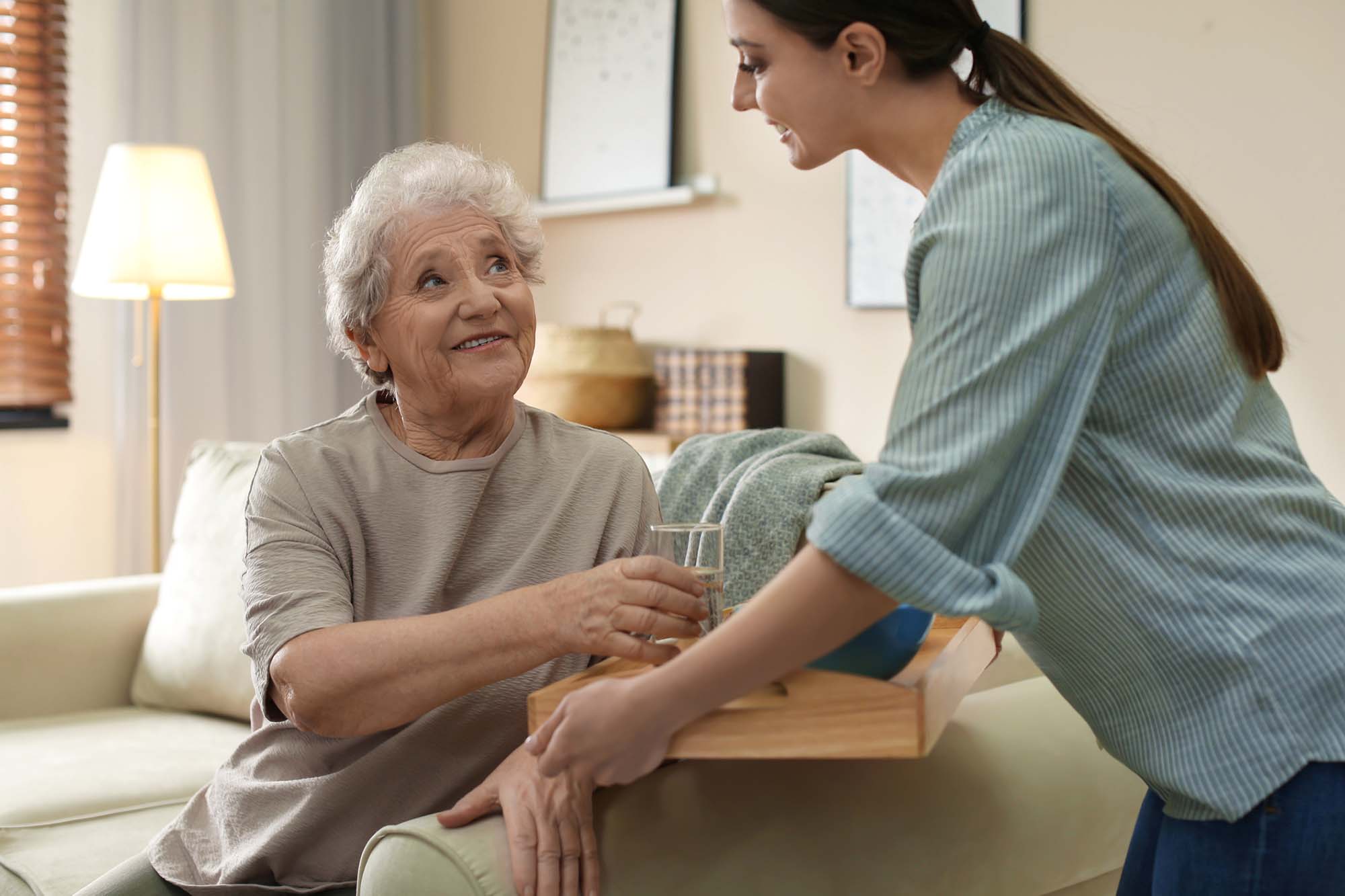 Carer offering elderly woman water